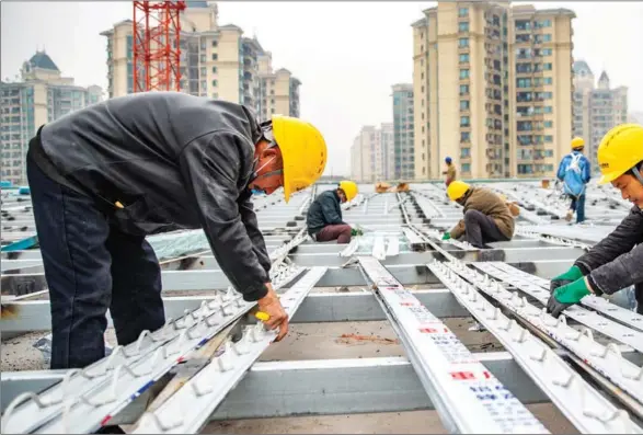  ?? HUANG WEI / XINHUA ?? Workers install decorative lights for a key movie and television production base being built in Chongqing last month after constructi­on resumed.