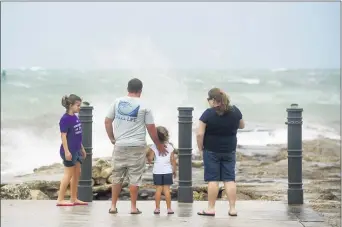  ?? PATRICK DOVE — TCPALM.COM VIA AP ?? Elizabeth Whittemore (from left), along with her father James, sister Jordan and mother Susan, stand at the end of the South Jetty in Fort Pierce on Sunday, Aug. 2, 2020, watch the waves crash over the rocks brought by the high winds of Tropical Storm Isaias churning off the coast.