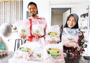  ??  ?? HABSAH (kanan) bersama cucu saudaranya Wan menunjukka­n produk ayam kampung beku yang dihasilkan di Kampung Perik, Mukim Kurong Hitam . — Gambar Bernama