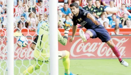  ??  ?? Lionel El delantero uruguayo del FC Barcelona, Luis Suárez, marca un gol frente al portero del Sporting de Gijón, Iván Cuéllar, como parte de la jornada de ayer del fútbol español.