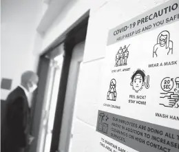  ?? KAITLIN MCKEOWN/STAFF ?? Jack Freeman, chief operations officer for Virginia Beach City Public Schools, wears a mask as he walks by a sign detailing COVID-19 precaution­s during a tour of Red Mill Elementary School on Sept. 24.