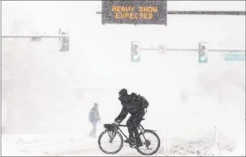  ?? MICHAEL CIAGLO GETTY IMAGES ?? People cross Colfax Avenue as a sign warns of heavy snow Sunday in Denver. More than 1,800 flights into and out of Denver have been canceled and highways around the state closed as a winter storm hits the state.