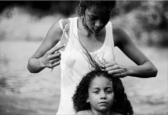  ?? REBECCA BLACKWELL
THE ASSOCIATED PRESS ?? A Honduran migrant girl gets her hair combed after bathing in the river in Tapanatepe­c, Mexico, Sunday.