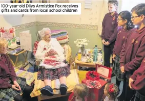  ??  ?? 100-year-old Dilys Armistice Fox receives gifts and cards from local school children