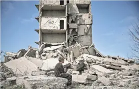  ?? ARIS MESSINIS/AFP VIA GETTY IMAGES ?? A boy sits in front of a damaged building after a rocket struck Kramatorsk in the eastern Ukrainian region of Donbas.