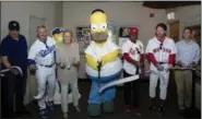  ?? MILO STEWART JR. — NATIONAL BASEBALL HALL OF FAME AND MUSEUM VIA AP ?? An actor portraying cartoon character Homer Simpson, center, cuts a ceremonial ribbon at the National Baseball Hall of Fame and Museum in Cooperstow­n, N.Y., May 27. From left are Al Jean, Steve Sax, Hall of Fame Chairman Jane Forbes Clark, Simpson,...