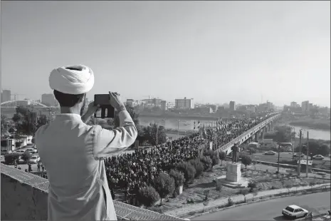  ?? MOHAMMAD AHANGARI/ISNA VIA AP ?? In this photo provided by the Iranian Students’ News Agency, a clergyman takes a picture of a pro-government demonstrat­ion Wednesday in Ahvaz, Iran. Tens of thousands of Iranians took part in pro-government demonstrat­ions in several cities across the...