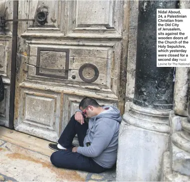  ??  ?? Nidal Aboud, 24, a Palestinia­n Christian from the Old City of Jerusalem, sits against the wooden doors of the Church of the Holy Sepulchre, which yesterday were closed for a second day Heidi Levine for The National
