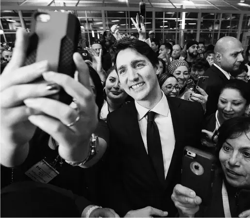  ?? Nathan
Denett
e / The Cana dian Press ?? Justin Trudeau poses for selfies with workers before he greets refugees from Syria at Pearson Internatio­nal Airport
in Toronto. The refugee crisis is just one area where the PM is taking bold action, Michael Den Tandt writes.