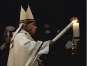  ?? REMO CASILLI/REUTERS ?? Pope Francis lights a candle Saturday at an Easter vigil service in a nearly empty St. Peter’s Basilica.