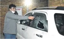  ??  ?? Carlos Tavárez señalando los impactos de bala que tuvo en la ventanilla de su camioneta durante el asalto.