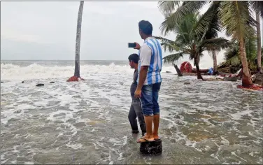  ?? REUTERS ?? A man uses his mobile phone to take photograph­s of tides on the shores of the Arabian Sea, after flooding caused by Cyclone Ockhi in the coastal village of Chellanam in Kerala, on Saturday. The bodies of four Kerala fishermen were recovered on...