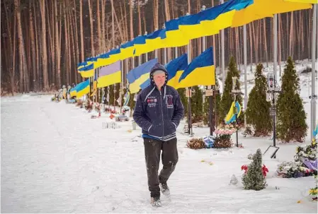  ?? Daniel Cole/Associated Press ?? An undertaker walks by the Alley of Heroes at the Irpin Cemetery in Irpin, Ukraine. Fighting in the Donbas region of eastern Ukraine are expected to heat up ahead of the first anniversar­y of the Russian invasion.