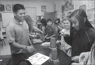  ?? NWA Democrat-Gazette/FLIP PUTTHOFF ?? Ryan Quintana, world history and science teacher at Lingle Middle School in Rogers, works with students Friday. District officials were persistent in recruiting Quintana. He eventually agreed to come visit. That visit convinced him Rogers was where he...