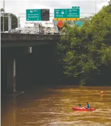  ?? THE ASSOCIATED PRESS ?? Traffic builds on Interstate 285 Wednesday as a kayaker floats underneath on the Chattahooc­hee River in Atlanta.