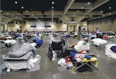  ?? NELVIN C. CEPEDA U-T PHOTOS ?? James Sneed gets comfortabl­e on his cot at the San Diego Convention Center homeless shelter last week. Sneed moved into the shelter last year after a leg injury and will now move to Golden Hall when it closes.