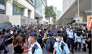  ?? — AFP photo ?? Police walk past supporters as they line up outside West Kowloon court in Hong Kong ahead of court appearance­s by dozens of dissidents charged with subversion in the largest use yet of Beijing’s sweeping new national security law.