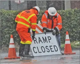  ?? Dan Watson/The Signal (See additional photos on signalscv.com) ?? Heavy rain falls as Caltrans workers set up a ramp sign at the entrance to the southbound Interstate 5 from The Old Road near Rye Canyon Road in Valencia on Friday.