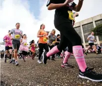  ?? Staff photos by Hunt Mercier ?? ■ TOP: Breast cancer survivors march in pink holding fans stating how many years they have been cancer free Saturday on Front Street in downtown Texarkana, Ark., before the Race for the Cure 5K event. The annual event lets survivors celebrate being cancer free and promotes awareness. ■ ABOVE: Runners for the competitiv­e Race for the Cure 5K event take off from the starting line.