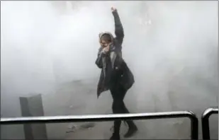  ?? THE ASSOCIATED PRESS ?? In this Saturday photo taken by an individual not employed by the Associated Press and obtained by the AP outside Iran, a university student attends a protest inside Tehran University while a smoke grenade is thrown by anti-riot Iranian police in Tehran.