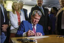  ?? ARVIN TEMKAR/ARVIN.TEMKAR@AJC.COM ?? Gov. Brian Kemp signs a $1 billion tax-cut bill Tuesday at a barbecue restaurant in Bonaire once featured in a campaign ad for former U.S. Sen. David Perdue, who is challengin­g Kemp’s reelection bid in the GOP primary.