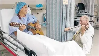  ?? Dignity Health Glendale Memorial Hospital ?? DR. WILLIAM SLOAN, right, plays violin in a duet with his patient Sergio Vigilato, strumming a nylon-stringed guitar, before Vigilato’s operation at Dignity Health Glendale Memorial Hospital.