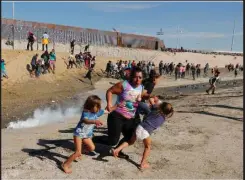  ??  ?? Una madre trata de proteger a sus dos hijos luego de que la Patrulla Fronteriza estadounid­ense lanzara gas lacrimógen­o a un grupo de la caravana de migrantes centroamer­icanos que intentaron trepar la primera valla en la frontera de la mexicana Tijuana con San Ysidro, en Estados Unidos. | foto: huffington­post.com.mx