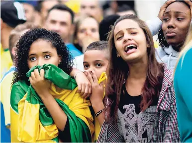  ??  ?? Brazilian football fans watch their team lose to Germany in the World Cup semifinal game on July 8, 2014.