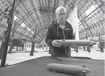  ?? MIKE CARDEW/ AKRON BEACON JOURNAL ?? Denny Carter, chief engineer LTA Research, talks about airships as he holds a model of Pathfinder 3 in the Akron Airdock in Akron in 2022. A model of the smaller Pathfinder 1 rests on a table. LTA Research, a company owned by Google co-founder Sergey Brin, plans to make airships at the facility.