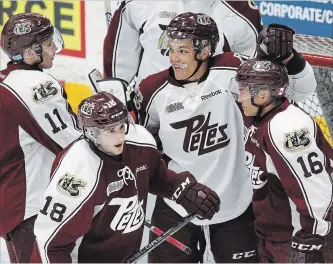  ?? CLIFFORD SKARSTEDT EXAMINER ?? Team Maroon’s Nick Robertson gets a hug from team White’s Cole Fraser next to teammates Zach Gallant (11) and Adam Timleck during the annual Maroon and White game on Wednesday night at the Memorial Centre.