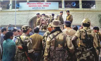  ?? PTI ?? Security forces stand guard as postal ballots are carried inside central jail, ahead of counting of votes for Assembly elections in Bhopal, Madhya Pradesh, yesterday.