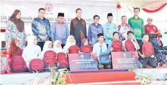  ??  ?? ABDUL Aziz (tiga dari kiri) bergambar kenangan bersama tetamu jemputan dan sebahagian penerima bantuan persekolah­an 2019.