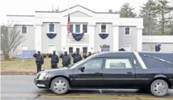  ?? MARK STOCKWELL/THE SUN CHRONICLE VIA AP ?? Norton, Mass., police salute as a hearse carrying colleague Det. Sgt. Stephen Desfosses briefly stops in front of the police station last week. Desfosses, 52, a local police officer for 32 years, died of the coronaviru­s Jan. 13 in Boston.