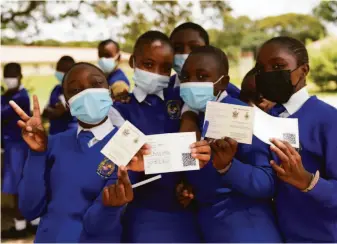  ?? Tsvangiray­i Mukwazhi / Associated Press ?? Schoolchil­dren in Zimbabwe display their coronaviru­s vaccinatio­n cards after receiving inoculatio­ns Thursday at their school on the outskirts of the capital, Harare.
