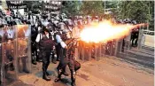  ??  ?? A police officer fires tear gas in an attempt to force the demonstrat­ors to disperse