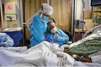  ?? Jae C. Hong / Associated Press ?? Romelia Navarro, right, is comforted by nurse Michele Younkin on July 31 while at the bedside of her dying husband, Antonio, in St. Jude Medical Center’s COVID-19 unit in Fullerton, Calif.