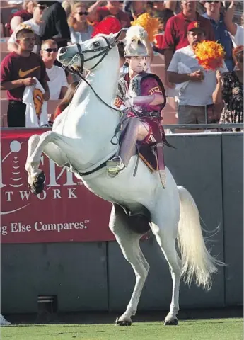  ?? Anacleto Rapping Los Angeles Times ?? RIDING IN ON A WHITE HORSE is a tradition before USC home games; Ardeshir Radpour guides Traveler V on the Coliseum field before a 1997 game against Florida State. Traveler IX debuts this fall.