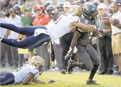  ?? PHOTOS BY PHELAN M. EBENHACK/AP ?? Central Florida running back Adrian Killins Jr. is tackled by Navy safety Jacob Springer after rushing for yardage as defensive back Michael McMorris (5) watches during the first half.