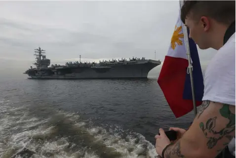  ?? (AP Photo/Bullit Marquez) ?? A U.S. sailor takes photos of the U.S. aircraft carrier USS Ronald Reagan (CVN 76) as it anchors off Manila Bay for a goodwill visit Tuesday, June 26, 2018 west of Manila, Philippine­s. The U.S. military has deployed the U.S. aircraft carrier to patrol...