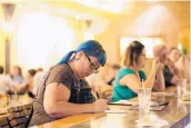  ??  ?? Sara Lehmann writes down her answers during the trivia night at O’Niell’s Pub in the Heights. She’s been doing Geeks Who Drink for 11 years. “It keeps my brain sharp,” she said.