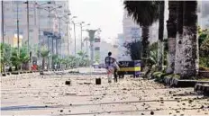  ??  ?? A man walks along a street covered in broken rocks in the canal city of Port Said yesterday following clashes the day before, which were triggered after a court sentenced 21 people to death over a football riot that killed more than 70.
