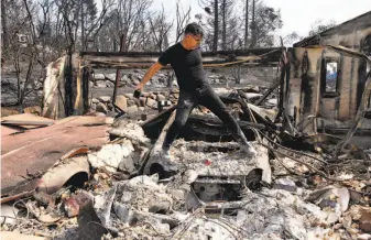  ?? Leah Millis / The Chronicle 2017 ?? Boback Emad climbs across one of his cars destroyed by the Tubbs Fire to take photos for his insurance carrier to show what’s left of his home in Santa Rosa’s Fountaingr­ove neighborho­od.