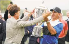  ?? Julio Cortez / Associated Press ?? PGA president Suzy Whaley, left, hands Brooks Koepka the Wanamaker Trophy after he won the PGA Championsh­ip Sunday.