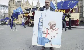  ?? AP ?? Political artist Kaya Mar poses for photograph­s with one of his paintings on the repeal bill next to an anti-Brexit protest outside the Houses of Parliament in London, Monday, September 11, 2017.