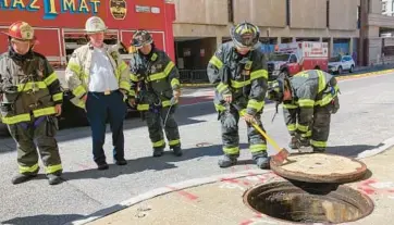  ?? KARL MERTON FERRON/STAFF ?? Removing a maintenanc­e hole cover on the sidewalk of Guilford Avenue, Baltimore fire department first responders investigat­e for a potential undergroun­d blaze at Guilford Avenue and East Lexington Street.