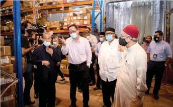  ?? — Bernama photo ?? Zulkifli (right) listens to a briefing by director of Lucky Frozen Sdn Bhd, See Weng Kee (second left) while inspecting the centre for imported frozen meat.