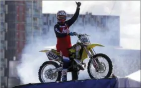  ?? ALASTAIR GRANT — THE ASSOCIATED PRESS FILE ?? In this file photo, Nitro Circus ringleader and stunt profession­al Travis Pastrana celebrates after he performed the first motorcycle backflip over the River Thames with a 75-foot wide gap between two floating barges, in London. Fifty years after Evel Knievel so famously wiped out trying to jump the fountain at Caesar’s Palace, action sports wild man Travis Pastrana will try to nail the stunt Sunday night in the finale of a triple-header tribute to the late daredevil.