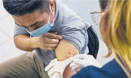  ?? KENNY HOLSTON/THE NEW YORK TIMES ?? A health care worker administer­s a COVID-19 vaccine Feb. 22 in Hagerstown, Maryland.