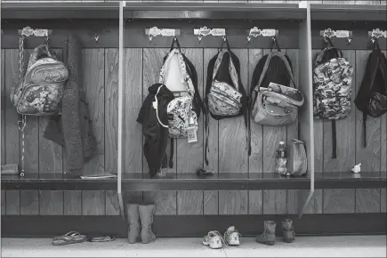  ?? PHOTOS BY ALYSSA SCHUKAR / THE NEW YORK TIMES ?? Backpacks hang in the hallways at the Arena Community Elementary School. Residents worry about what will happen to Arena, population 834, without the school. There isn’t much else on this two-lane stretch of U.S. Route 14: a gas station, a cheese...