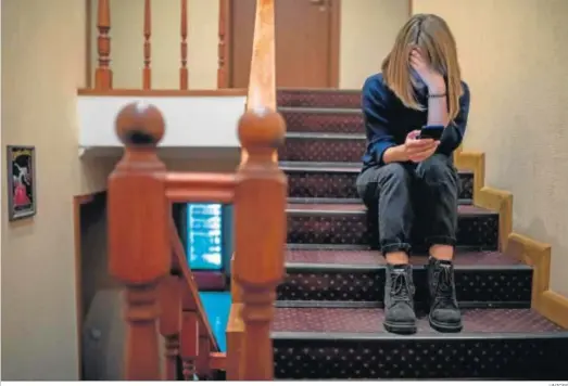  ?? UNICEF ?? Una niña mira su móvil sentada en las escaleras de su casa, durante el confinamie­nto.